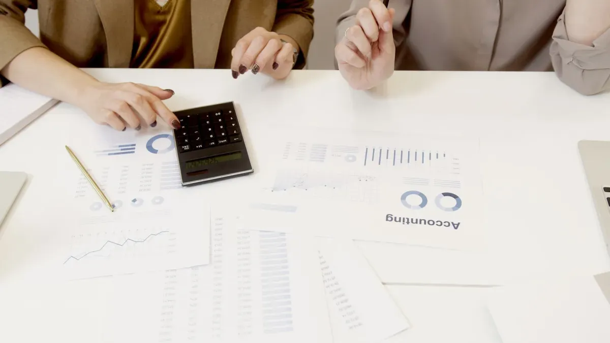 Mesa com relatórios contábeis e calculadora durante uma reunião