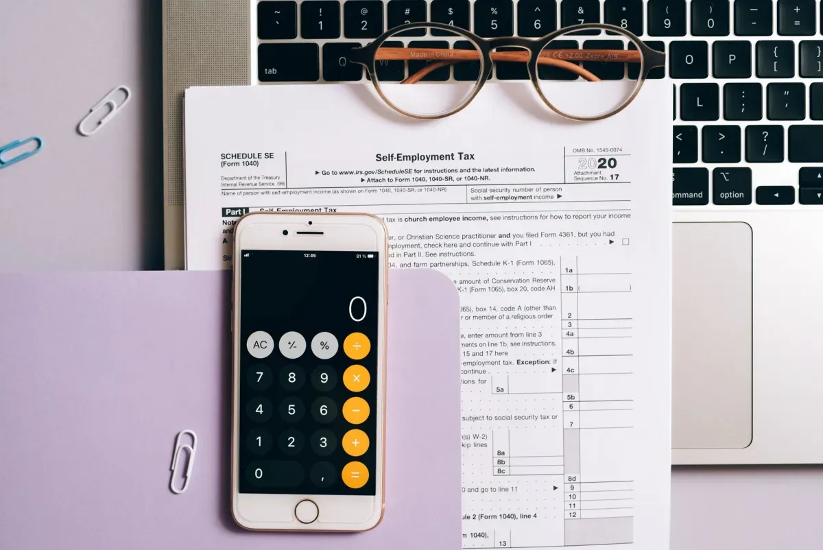 Formulário de imposto, calculadora no celular e óculos sobre a mesa