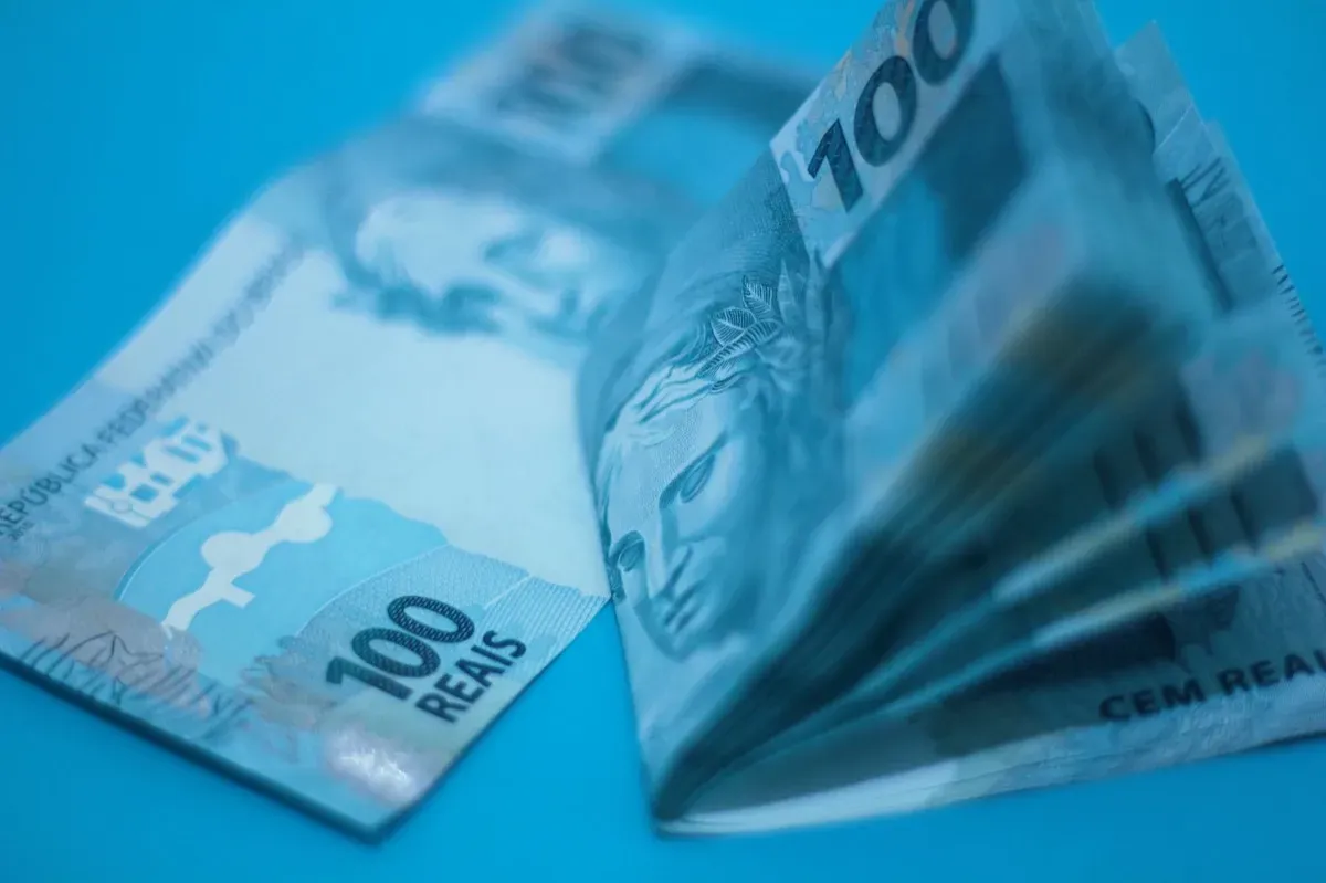 Notas de 100 reais sobre fundo azul
