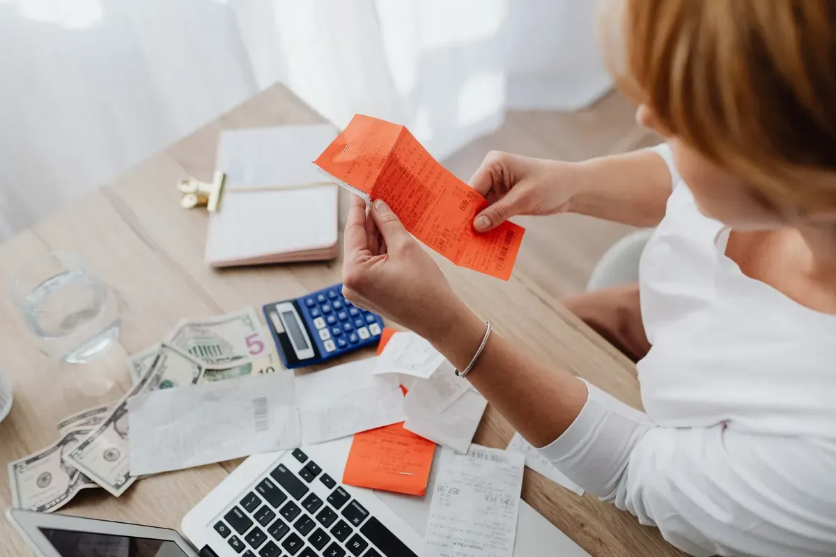 Empreendedora somando recibos na calculadora para acompanhar o faturamento