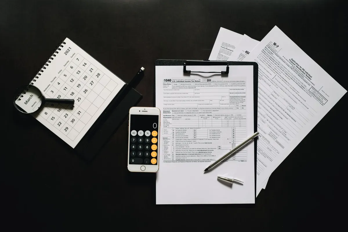Formulários, calculadora e calendário sobre a mesa, prontos para a apuração dos impostos do trimestre