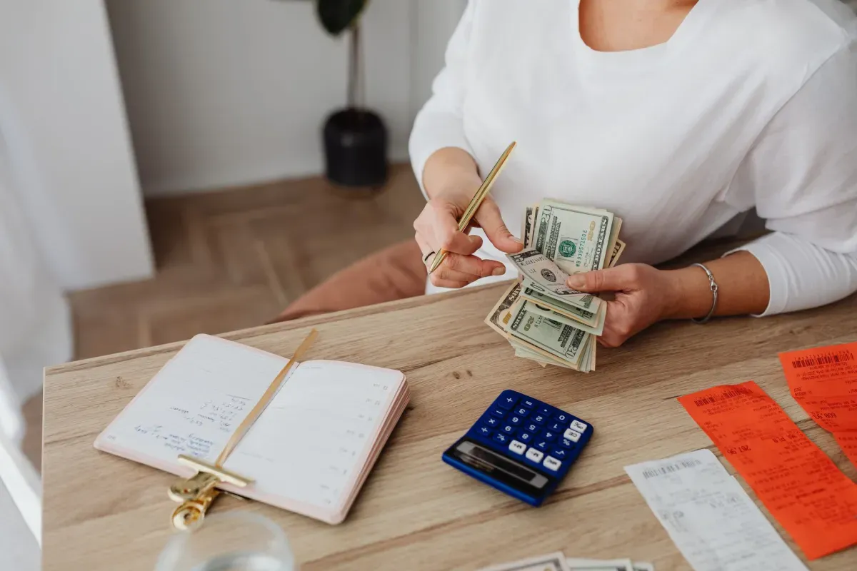 Mulher organizando as finanças com calculadora, dinheiro e recibos